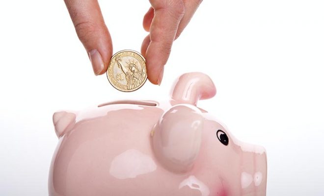 hand depositing coin in piggy bank