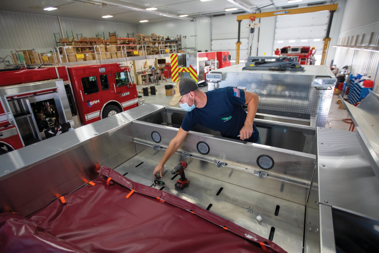 Brian Shivers attaches a fire hose cover to the top of a custom firetruck.