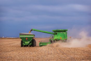 Rear view of a combine unloading soybeans into a grain cart on the go.