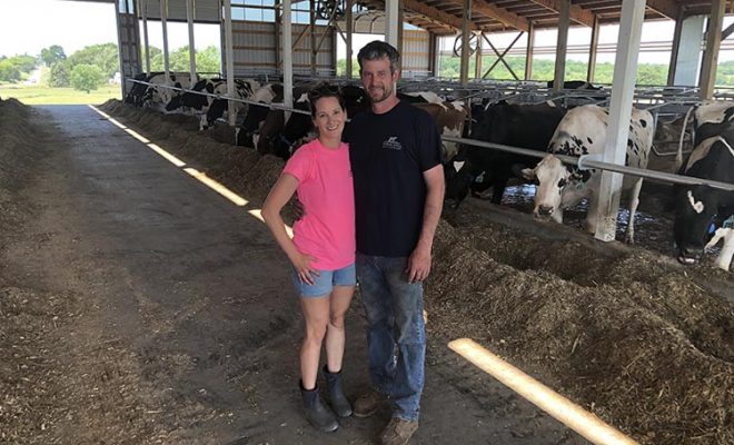 Katie and David Vanderstappen stand in a new free stall dairy barn they built to replace one burned to the ground in 2018.