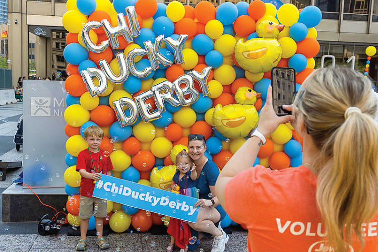 Volunteer takes a picture of a family in front of a duck balloon display
