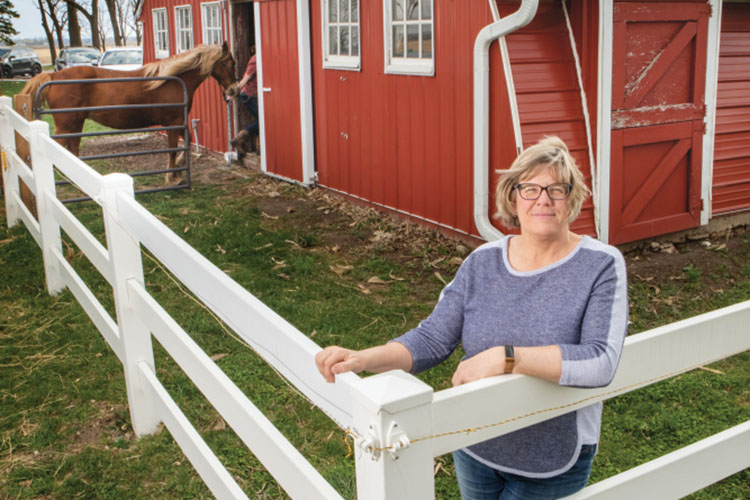 Janet McCabe stands outside horse stables on her family's fun