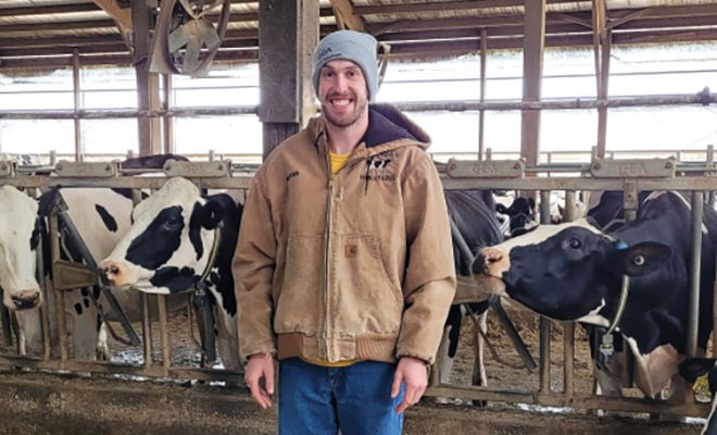 Aaron Mitchell stands in front of cattle at his farm