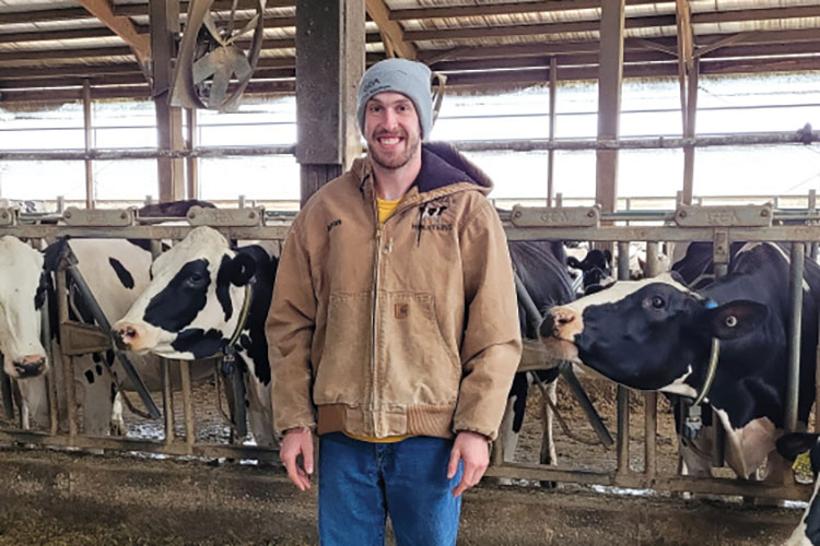 Aaron Mitchell stands in front of cattle at his farm