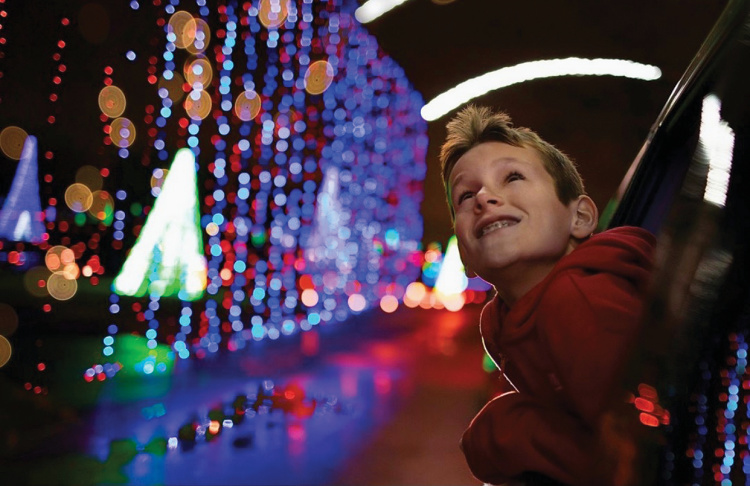 Child looking out the car window at holiday lights
