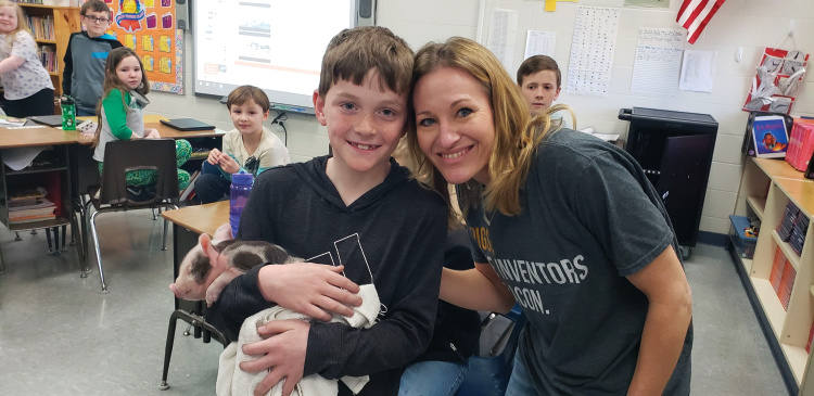 Cheryl Walsh poses with a student holding a baby pig
