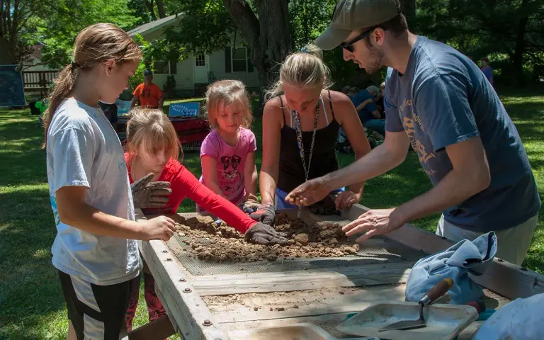 Kids dig through dirt during one of the Archeology Day activities