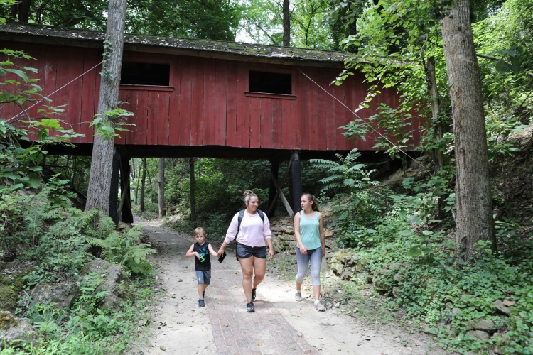 People walking under a covered bridge at Heritage Canyon