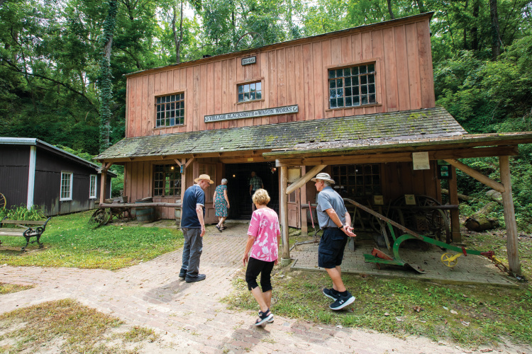 People visit a blacksmith building at Heritage Canyon