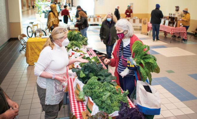 A woman purchases produce from a booth at the Carbondale winter market
