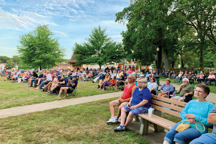 People sitting on benches enjoying an outdoor concert