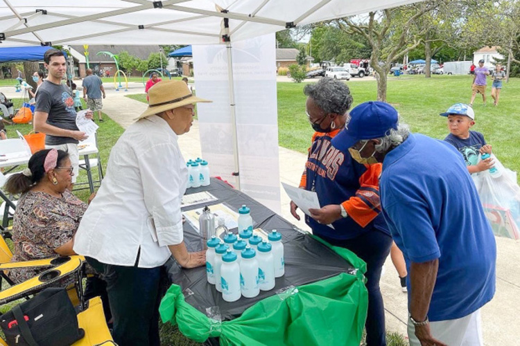 Woman hands out water bottles to guest at a Champaign County African American Heritage Trail event