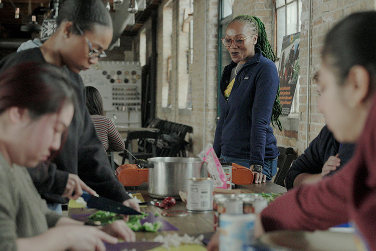 Selma Sims looks on as a group of volunteers prep a dish