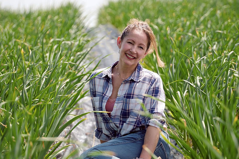 Sharon Pferschy siting in her garlic field at Garlic Breath Farm