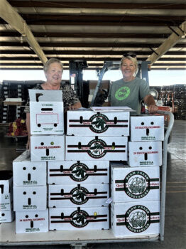 MaryBeth Massey and Susan Stollard standing behind a cart full of produce boxes