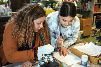 Zaina Darabaih and Mia Zepeda study cells under a microscope.