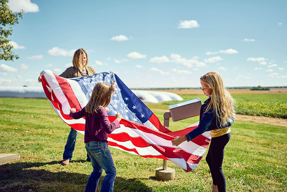 Casner and her daughters unfold an American flag at their family farm