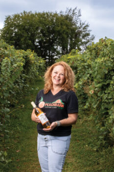 Jenny Schroeder holding a bottle of wine at her vineyard Peachbarn Winery and Cafe