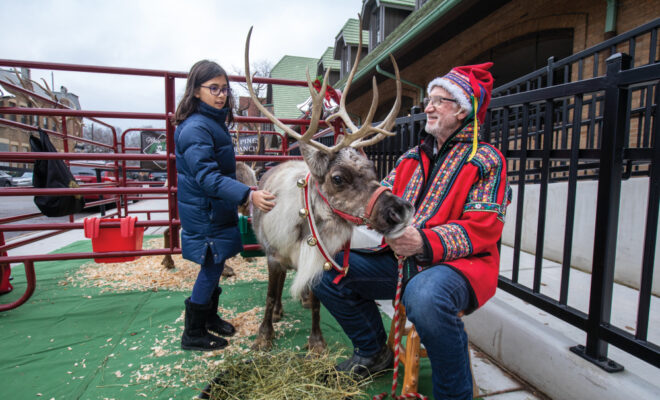 Randy Espe talks with a child as she pets the reindeer