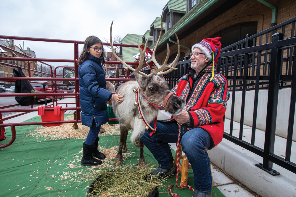 Randy Espe talks with a child as she pets the reindeer