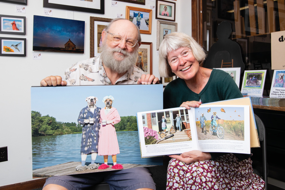 Cindy and Kirby Pringle holding artwork and books from their art business Dogtown Artworks