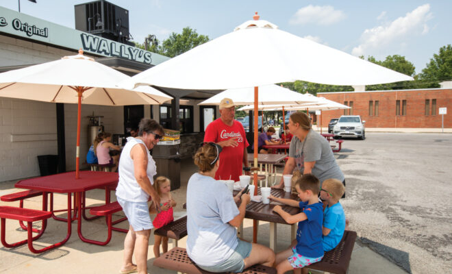 People eating at outdoor tables outside of Wally's Drive-In