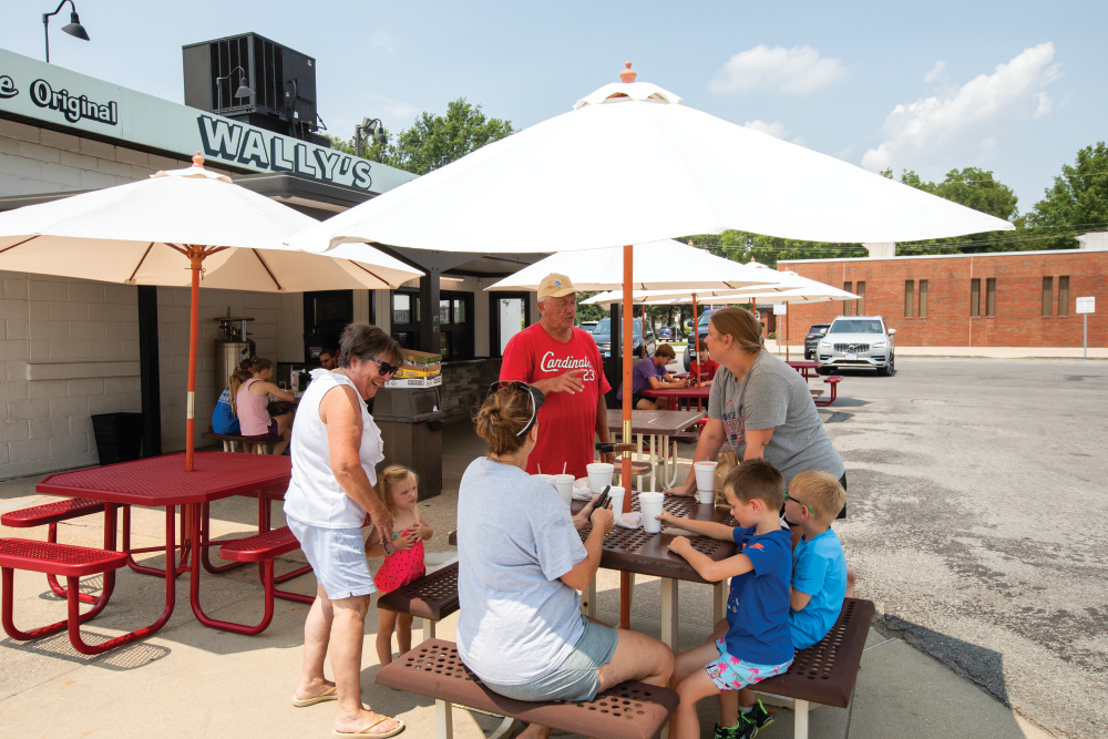 People eating at outdoor tables outside of Wally's Drive-In
