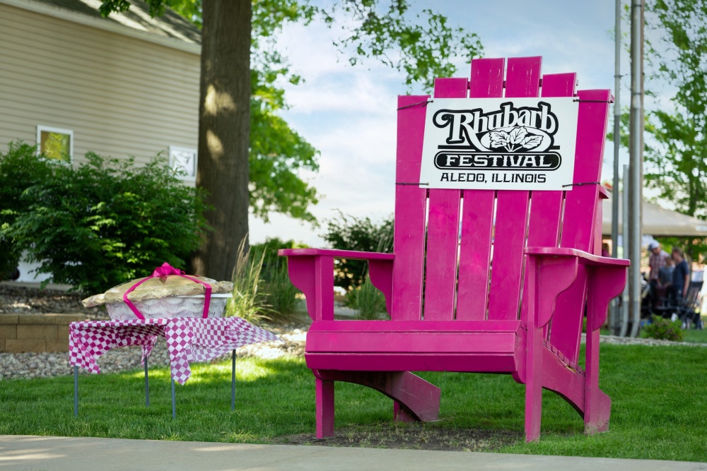 Large pink chair with a Aledo Rhubarb Fest sign on it