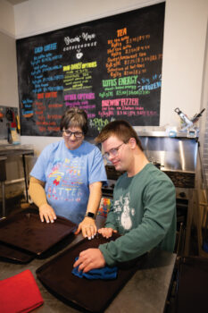 AAMP student Payton Burgener cleans trays with job coach Jenna Clements