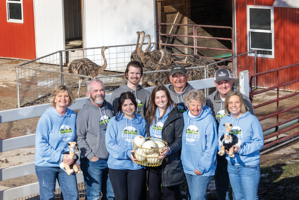 Erica, Paul and Amber Mollett, Brandyn and Meghan Fadler, Fred and Kathleen Salger, and Nathan and Patty Salger pose for a photo outside of one of the barns at Salger's Ostrich Products