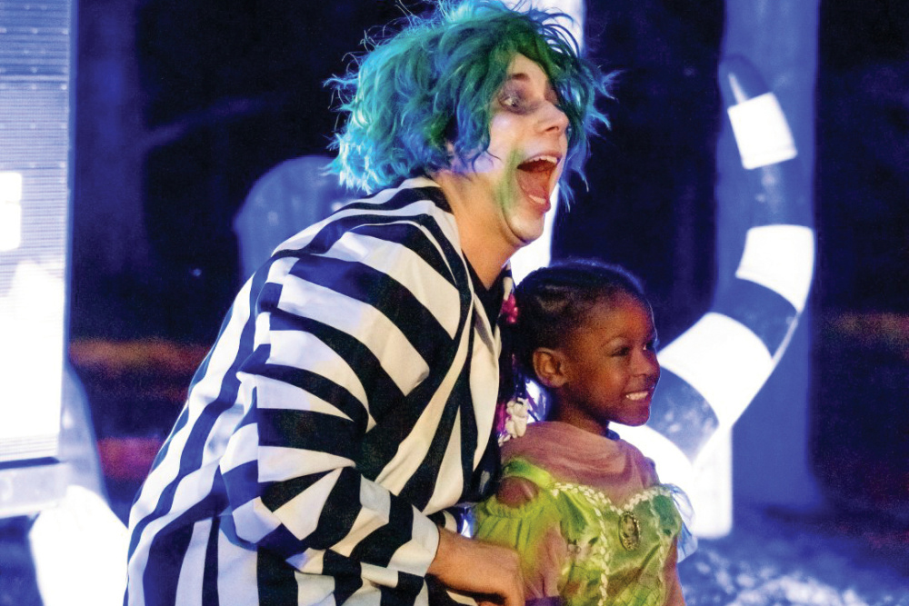 Man dressed as Beetlejuice posing for a photo with a little girl dressed as a princess 