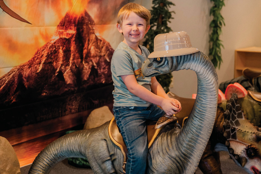 A child on a toy dinosaur at the Quincy Children's Museum, one of the things to do in Quincy