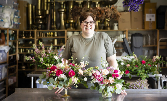 Candice Anderson standing in front of a floral arrangement at Pollen & Pastry