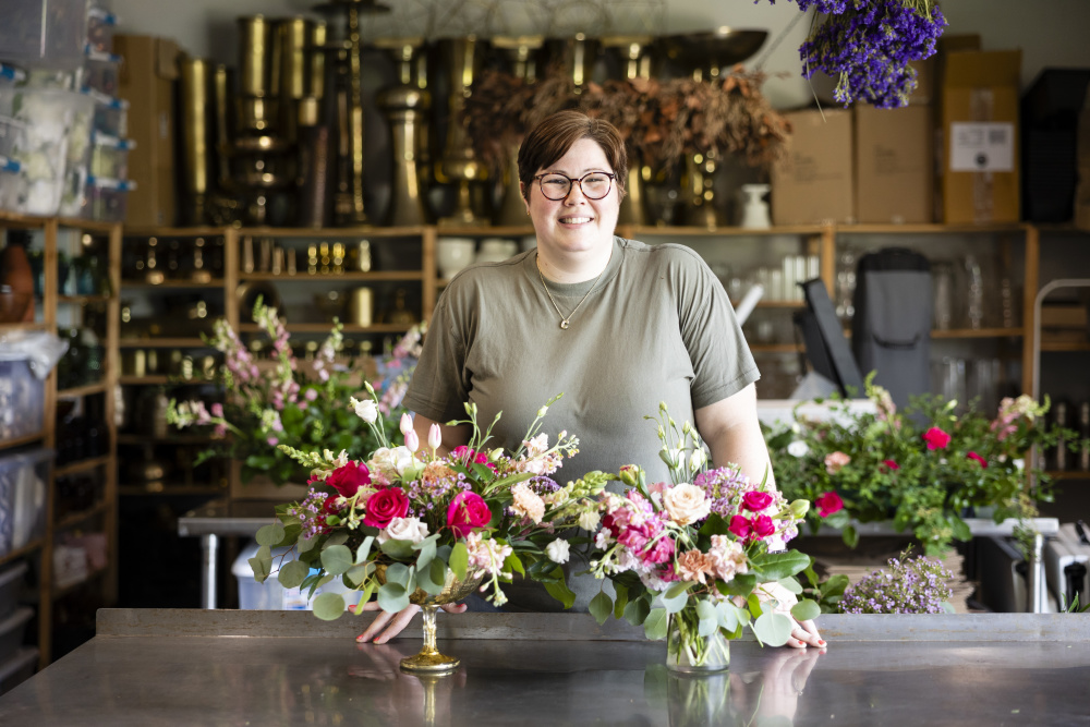 Candice Anderson standing in front of a floral arrangement at Pollen & Pastry