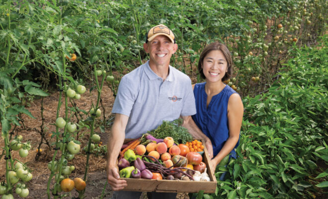 Ken and Nanam Myszka holding a box of produce in one of the fields at Epiphany Farms