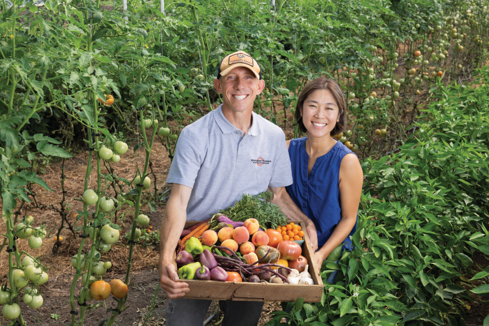 Ken and Nanam Myszka holding a box of produce in one of the fields at Epiphany Farms